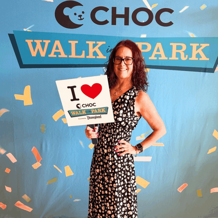 me in a black and white dress standing in front of a CHOC Walk in the park sign; help me fundraise in Disney style at the 2025 CHOC Walk at Disneyland