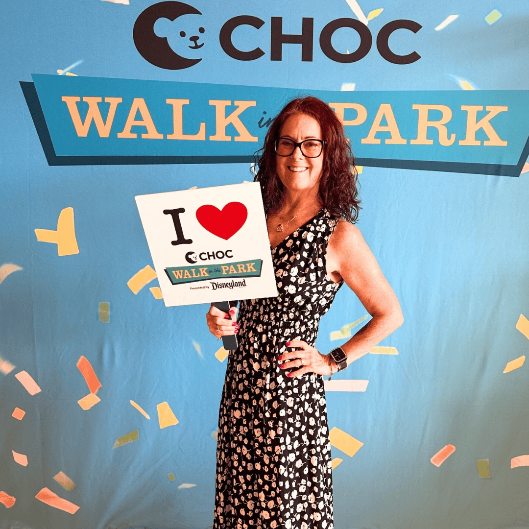 me in a black and white dress standing in front of a CHOC Walk in the park sign; help me fundraise in Disney style at the 2025 CHOC Walk at Disneyland