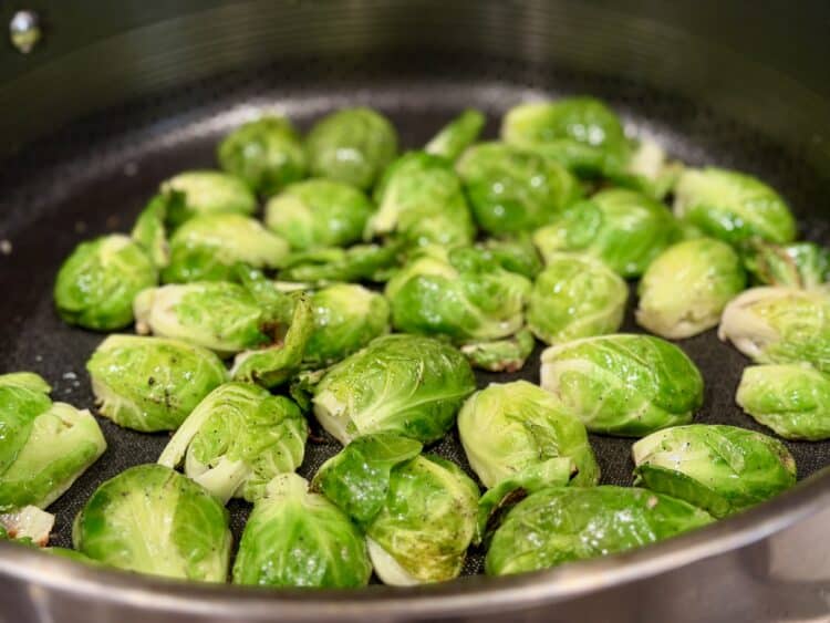 Brussels sprouts cut in half and searing, cut side down.