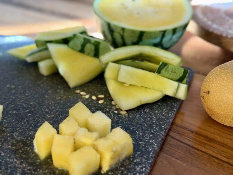 Golden watermelon being chopped up for the citrus watermelon and asian pear salad recipe