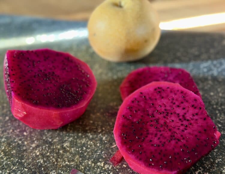 slices of a bright red dragonfruit on a cutting board