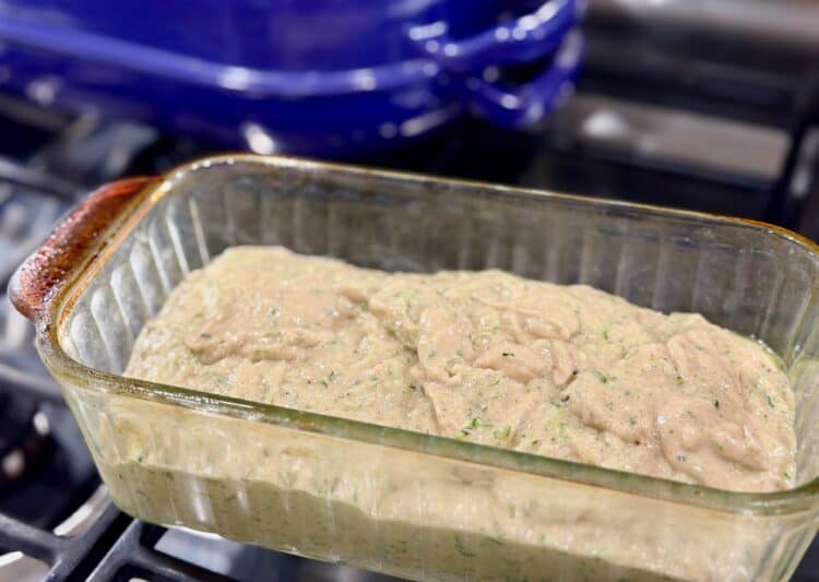 high-protein zucchini bread batter in a glass baking loaf pan sitting on the stovetop